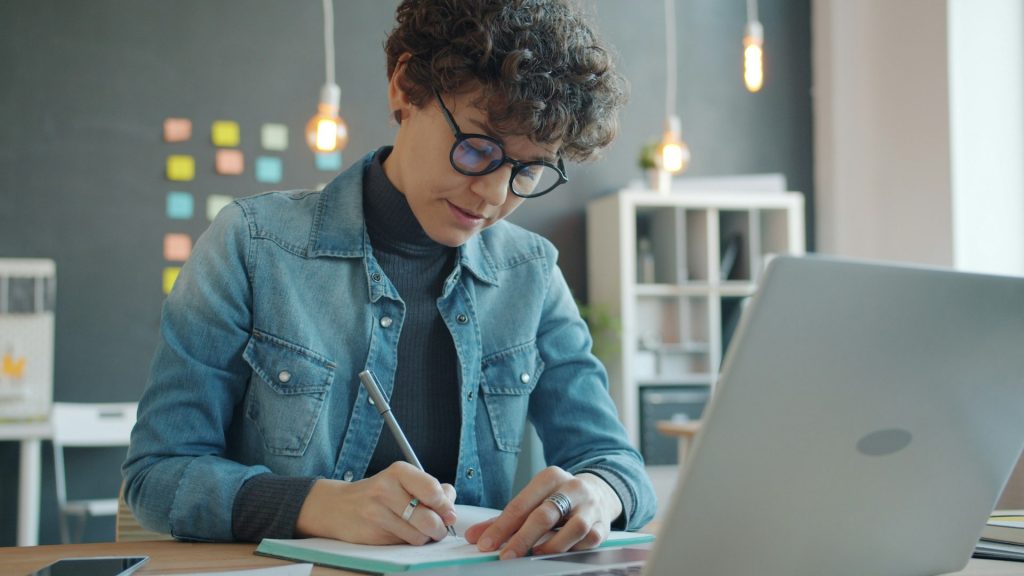 Gründerin arbeitet am Laptop an ihrem Businessplan für ein AVGS-Gründercoaching vom Jobcenter