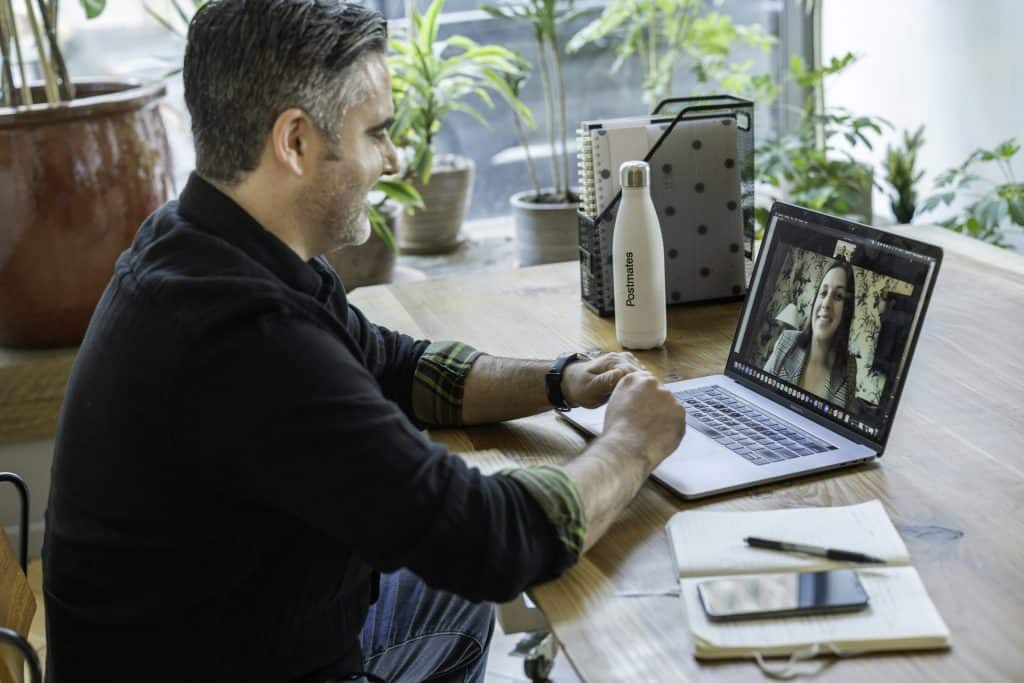 Mann am Schreibtisch zu Hause im Videocall mit seiner Coachin – AVGS-Gründercoaching online